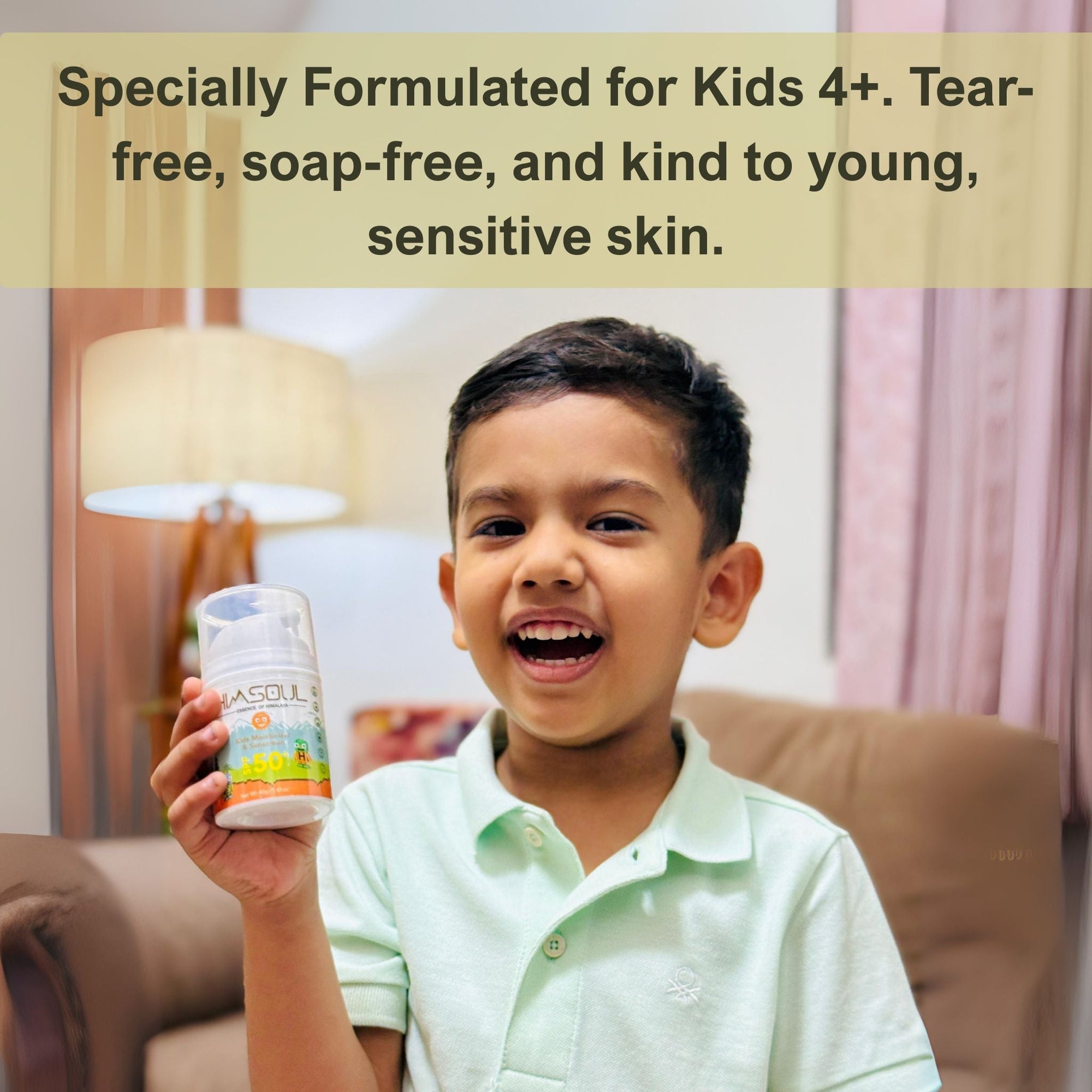 A happy young boy holding a bottle of Himsoul Kids Moisturizer and Sunscreen SPF 50+, highlighting its tear-free and soap-free formula for sensitive skin.